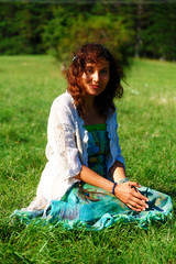 young girl in beautiful ethno dress praying on meadow.