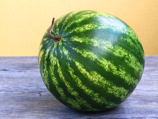 the whole watermelon on gray table and yellow background