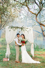 Lovely wedding couple is standing and posing outside