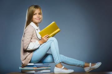 school concept. girl sitting on books and holding a book in hand