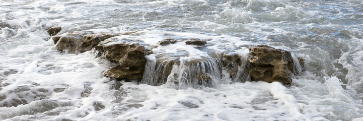 Breaking waves with foam on the rocky coast