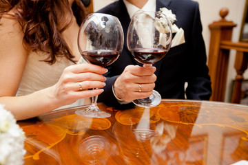 Wedding couple is showing rings while drinking red wine