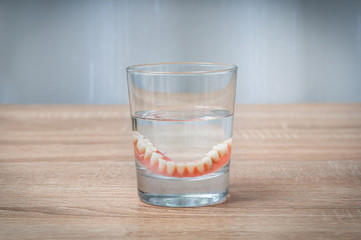 False teeth swim in transparent water glass