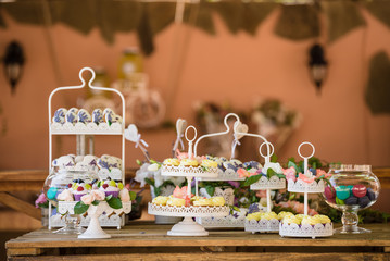 Delicious candy bar Dessert table for outdoor party. Ombre cake, cupcakes, sweetness, berries and flowers