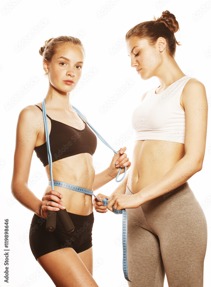 Wall mural two sport girls measuring themselves isolated on white