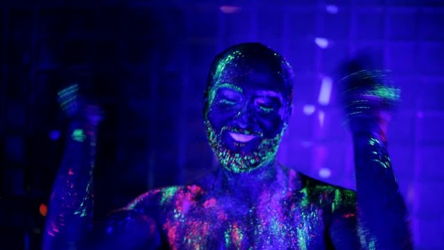 man painted fluorescent powder dance in ultraviolet light