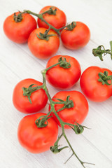 Fototapeta na wymiar Picture of vine tomatoes on a white wooden background
