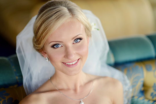 Beauty bride in bridal gown with lace veil indoors. Beautiful model girl in a white wedding dress. Female portrait of cute lady. Woman with hairstyle