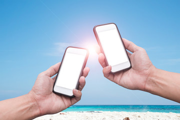 Hand holding Smartphone over beach and blue sky background