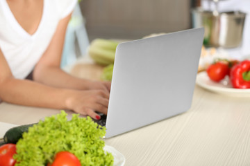 Obraz na płótnie Canvas Girl with laptop on kitchen. Food blogger concept