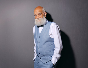 Elderly bearded man in stylish suit on grey background