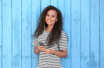 African American girl listening music on wooden background