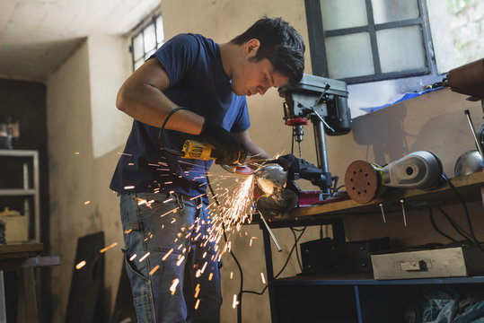 Forger grinding metal in workshop