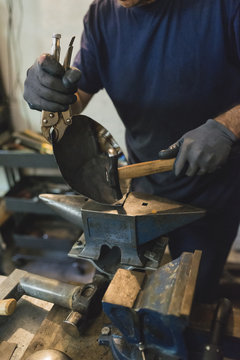 Forger hammering metal in workshop