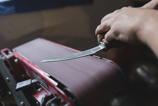 Forger sharpening knife in workshop