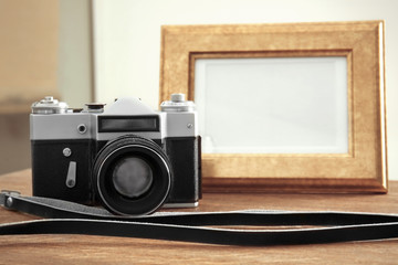 Vintage camera and frame on wooden table