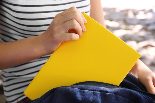 Woman Putting Book Into Rucksack, Close Up