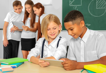 Schoolchildren sitting in classroom with tablet computer