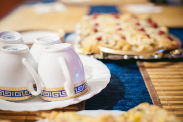 
home baked biscuit charlotte. Delicious freshly baked gingerbread sweet cake with apples. served on a table in a golden platter, cut square pieces. tableware tea set cups