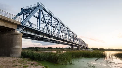 Fotobehang Bruggen railway bridge with metal rails near river  © Martins Vanags