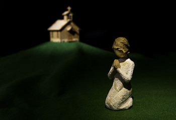 Prayer doll on green grass with church on hill