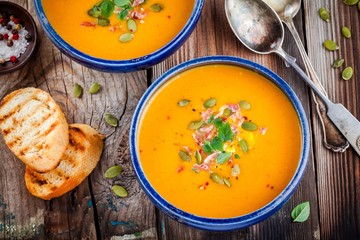 homemade autumn butternut squash soup with pumpkin seeds, bacon and basil
