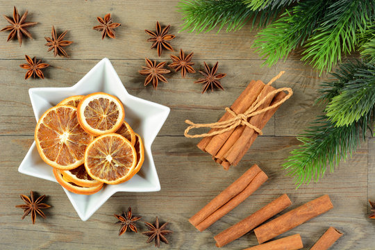 Sternanis, Zimt, Zimstangen, getrocknete Orangen und Tannenzweige als Deko zu Weihnachten
