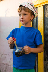 Obrazy na Szkle  Chłopiec wykonuje prace malarskie malować na zewnątrz latem