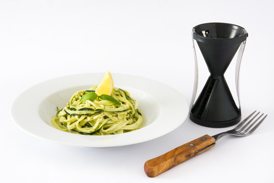 Zucchini noodles with pesto sauce and spiralizer isolated on white background

