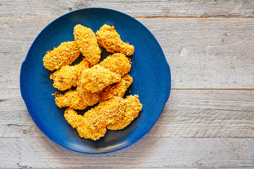 Baked Corn Flake Coated Chicken Wings on a Blue Ceramic Plate © Ana-Maria Tegzes