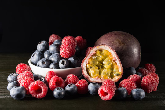 Rspberry and blueberry with a passionfruit, on dark background,