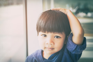 Asian boy is touching his head and hair thinking.