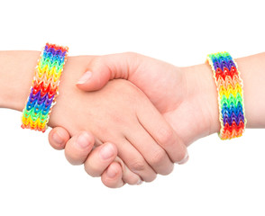 young girls shaking hands with a bracelet patterned as the rainbow. isolated on white