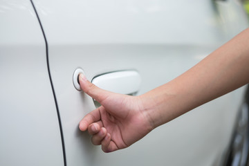 Woman's hand press on locking button of the car's door with keyl