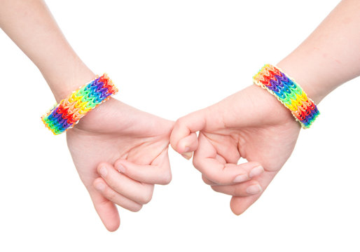 two woman's hands with a bracelet patterned as the rainbow flag together. isolated on white