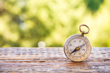 Vintage compass on wooden table and bokeh background