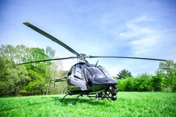 Hélicoptère noir avec des rayures grises debout sur un terrain d& 39 herbe verte se préparant à survoler le ciel bleu.