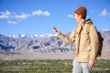 Asian young traveler looking at compass in Himalaya mountain view background