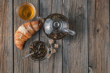 Breakfast with herbal tea and croissant on wooden vintage table