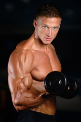 Fototapeta na wymiar Handsome muscular bodybuilder man doing exercises in gym