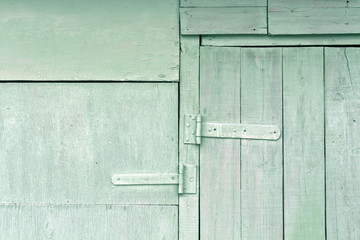 Old cyan wooden hangar door with metal hinges.