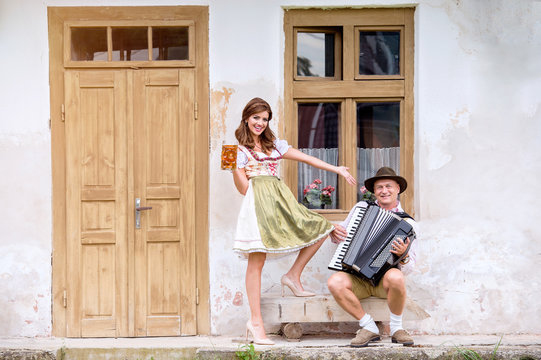 Couple in traditional bavarian clothes with beer and accordion