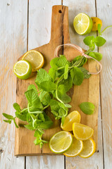 Sliced Lime and lemons with bunch of fresh mint on  wooden chopp