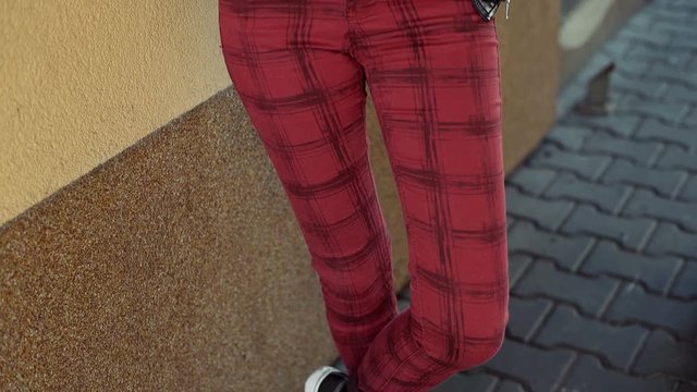 Punk girl leaning on the wall and browsing internet on tablet, steadycam shot
