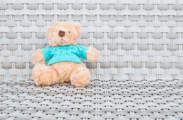 Closeup a fabric bear doll sit on wood weave chair texture background with copy space