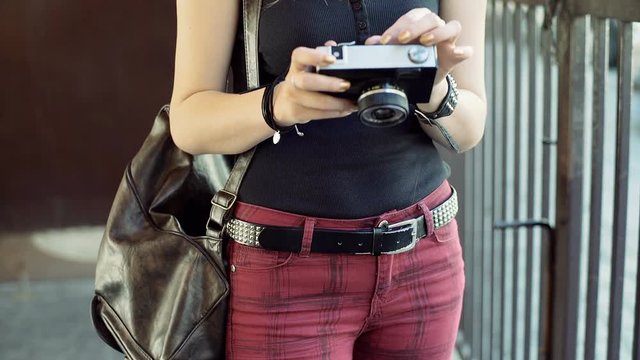 Punk girl holding old camera and browsing photos on it
