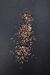 white, red and black quinoa on slate