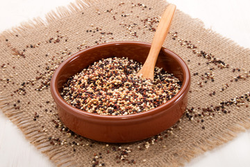 white, red and black quinoa in brown earthenware bowl