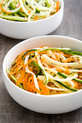 Carrot and zucchini noodles on a rustic wooden table

