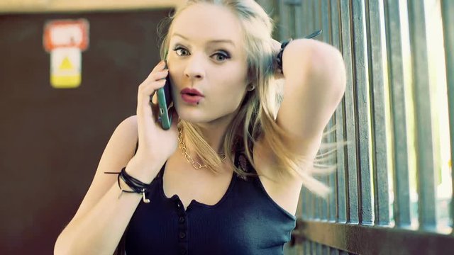 Punk girl having an argument while talking on cellphone and looking mad to the camera
